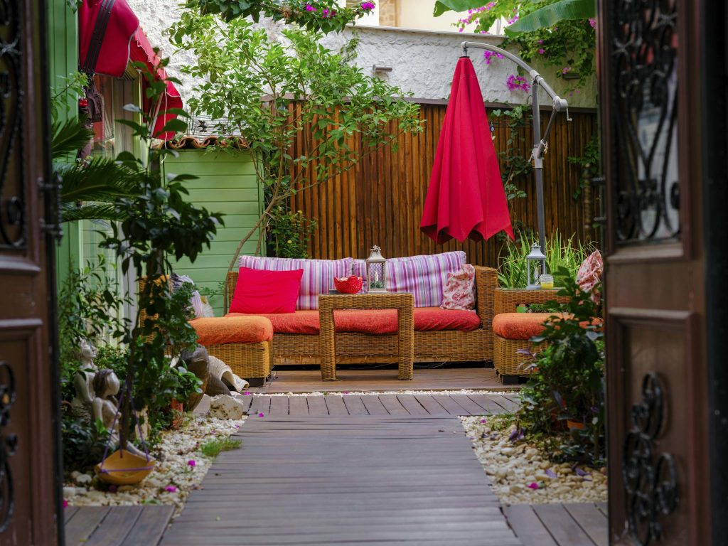Vibrant outdoor patio with wicker furniture, bright cushions, and lush greenery for a cozy retreat.