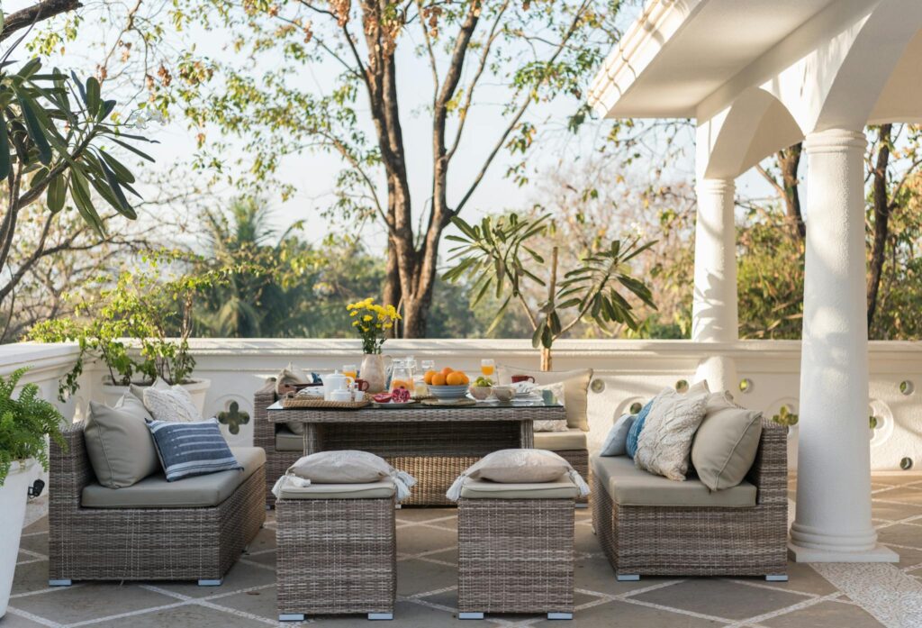 Cozy outdoor patio with wicker furniture, plants, and dining setup perfect for relaxing and entertaining.